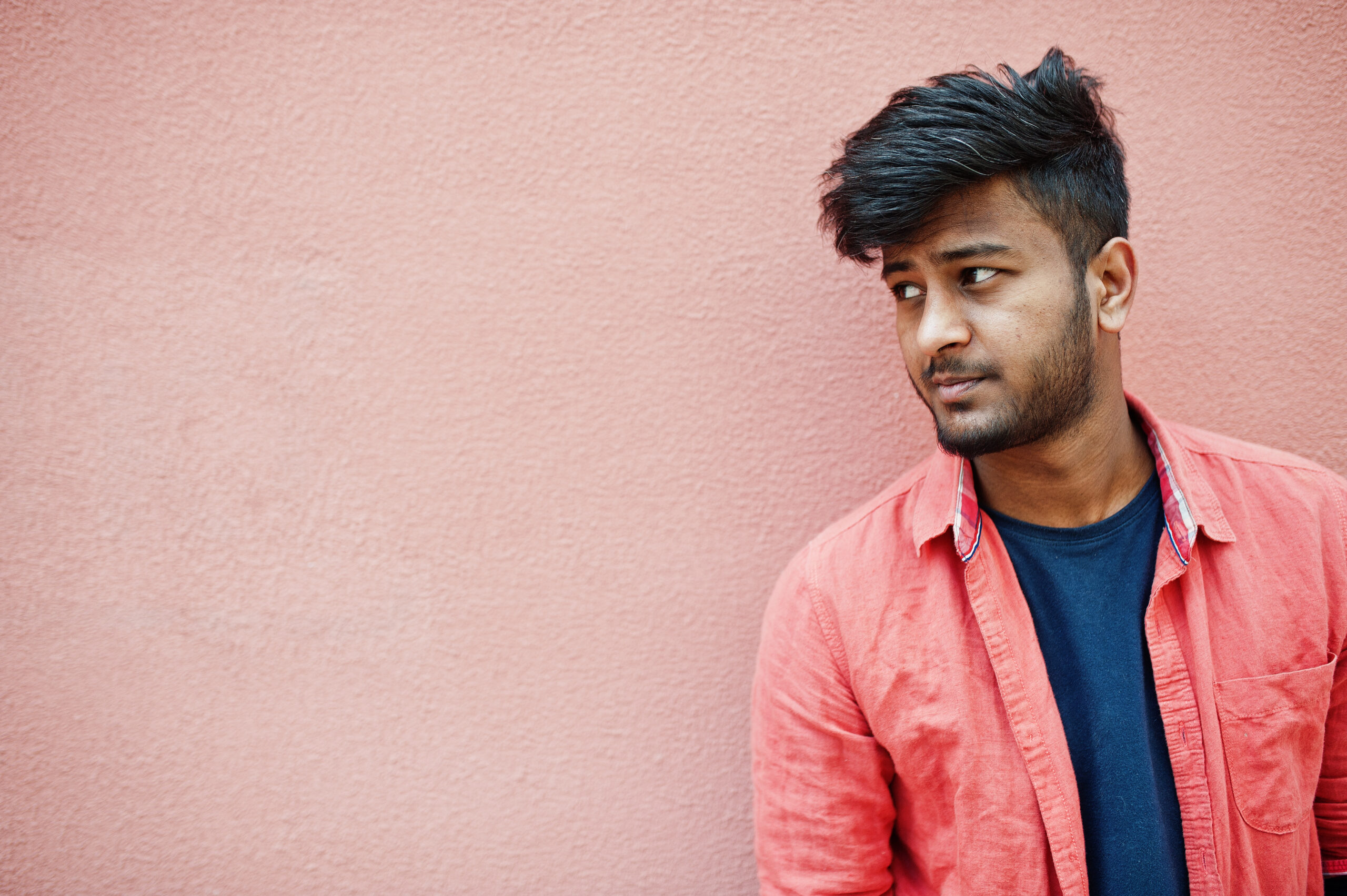 Portrait of young stylish indian man model isolated on pink wall